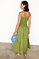 Olive Lola Mid-axi Dress with a ruched strapless top and flowy green cotton skirt, styled with a blue clutch.