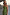 Thumbnail for Olive Lola Mid-axi Dress with a strapless ruched bodice and gathered skirt, styled with layered gold necklaces.