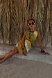Green Ombre Deia Dress with earthy tones and raffia trim, styled in a sunny vacation setting.