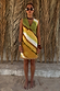 Green Ombre Deia Dress with yellow tones and raffia trim, styled for a vacation against palm leaves.