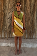 Green Ombre Deia Dress with yellow tones and raffia trim, styled for a vacation against palm leaves.