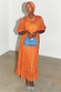 Orange Jacquard Bibi Dress featuring gold diamond patterns and puffball sleeves, styled with a matching headwrap.