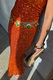 Orange Sequin Dorris Skirt in burnt orange sequins, styled with a gold-toned belt and a beaded clutch.