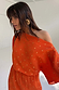 Orange Tilly Dress with a gold fleck print, featuring a draped asymmetric shoulder and pleated fabric.