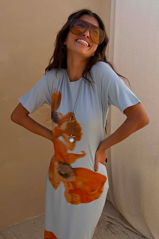Orange Acetate Visor Sunglasses with 70s-inspired tinted lenses, worn by a smiling model in a blue floral dress.