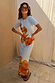 Orange Acetate Visor Sunglasses with tinted lenses worn with a light blue floral ribbed midi dress.