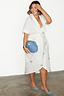 White cotton linen Brooklyn wrap dress with gold metallic palm flecks, styled with blue accessories.