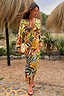 Cream Palm Leaf Emma Dress with a tropical print and v-neckline on a model in an outdoor vacation setting.