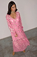 Pink Jacquard Harmony Dress with gold animal print, featuring a tassel neckline and tiered hem on a model.