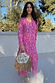 Pink Jacquard Harmony Dress with a gold animal print and neck tassels, styled with a fringed straw bag.