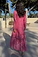 Pink Jacquard Harmony Dress with gold animal print and tiered skirt, shown from the back on a sunny terrace.