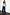 Thumbnail for Navy Pinstripe Arden Trousers in a wide-leg fit, styled with a grey knitted jumper and leopard print shoes.