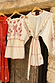 Cream and Red Pollenca Mini Dress with embroidered palm trees and scalloped edges hanging on a wooden door.