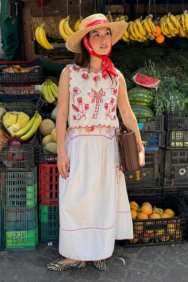 Cream cotton Pollenca Top with red palm tree embroidery and scallop hem, styled as a co-ord at a fruit market stall.