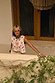 Cream Pollenca Top with red embroidered palm tree motifs and scallop edge trim, worn on a vacation balcony.