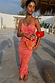 Coral Fawn Poppy Aria dress in pink with orange poppy motifs and white dots, styled with a matching beaded bag.