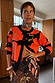 Thumbnail for Black Poppy Cardigan with an iconic red poppy print and wide sleeves, styled over a patterned mesh dress.