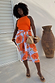 Blue Poppy Jaspre Skirt with orange floral print, styled as a wrap skirt with a bright orange ribbed vest.