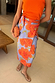 Thumbnail for Blue Poppy Jaspre Skirt with orange floral print and wrap tie, styled with an orange top and beaded clutch.