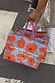 Blue poppy gift bags with orange florals and pink handles, held in London and featuring the feel good dressing slogan.