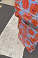 Stacked blue Poppy Gift Bags with orange floral print, pink handles, and Feel Good Dressing branding on a London street.