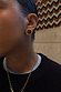 Deloris Red Circle Earrings in textured brushed brass with a semi-precious red stone, shown on a model.