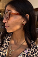 Deloris Red Circle Earrings in textured brushed brass with a red stone, styled with a leopard print top.