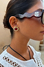 Deloris Red Circle Earrings in textured brushed brass with a red stone, shown on a model wearing tortoiseshell sunglasses.