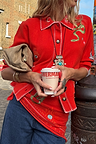 Red Mystical Cardigan with jacquard motifs and blanket stitch detailing, styled with a tan clutch and jeans.