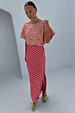 Pink and red jacquard Tilly dress with gold dots and a side slit, worn by a model.