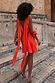 Tomato Mini Sophie Dress in red with a draped back and detachable scarf ties, shown on stone steps.