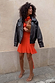 Tomato Mini Sophie Dress in red with a cowl neck and floaty skirt, styled with a black leather jacket and leopard clutch.