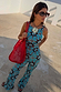 Red Wiggle Arm Acetate Sunglasses with red tortoise frames and dark lenses, styled with a blue sun-print co-ord and red bag.