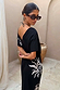 Red tortoise acetate sunglasses with wiggle arms and dark lenses, worn by a model in a black sun print dress.