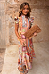 Dolce Vita Remi Dress in a sunset-toned patchwork print with a high neck and ruffle sleeves against a stone wall.