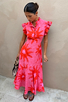Pink Soleil Remi Dress featuring red sun motifs, pleated frill sleeves and an asymmetrical skirt on a model.