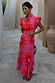 Pink Soleil Remi Dress featuring red sun motifs, pleated frill details and an asymmetrical skirt.