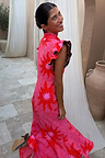 Pink Soleil Remi Dress with red sun motifs and leopard lining on pleated frill sleeves, shown on a smiling woman.