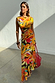 Rio A-Symmetric Skirt in a multi-coloured fruit print, styled with a matching co-ord top and red bag.