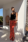 Red Rosie Maxi Skirt with a floral and leopard print, styled with a black vest and neck scarf for a vacation look.