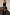 Thumbnail for Black Vegan Leather Ruffle Mini Jaspre Skirt with ruffle detailing, styled with a black top and knee-high boots.