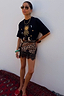 Thumbnail for Running Wilder T-shirt in black cotton with iconic sun and leopard print, styled with a mini skirt.