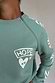 Thumbnail for Sage Sundazed Accessible Sweatshirt in green with a cream HOPE graphic and concealed shoulder zip for treatment access.