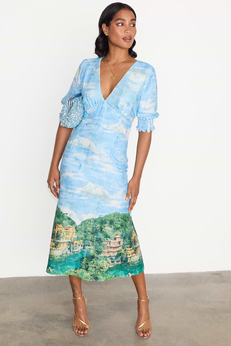 Scenery May Dress Petite featuring a blue Lake Como landscape print, deep V-neckline and short ruched sleeves.