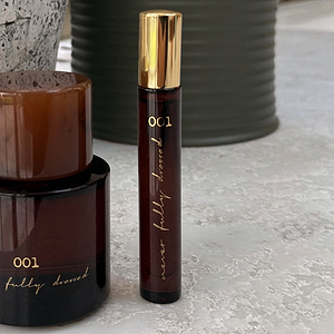 NFD Eau De Parfum 001 10ml travel bottle in amber glass with a gold cap and Never Fully Dressed gold script.