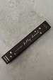 Dark brown NFD Eau De Parfum 001 10ml box with gold foil script and celestial icons on a stone surface.