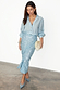 Model wearing the iconic Ice Blue Sequin Jaspre Skirt with a light blue shirt and crystal-buckle heels.