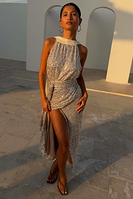 Silver sequin maxi Jaspre wrap skirt on a model in an outdoor setting with white archways.