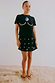 Black Crochet Shell Wrap Skirt with gold shell details, styled with a black tee and beaded sandals on sand.