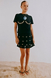 Black Crochet Shell Wrap Skirt with gold shell details, styled with a black tee and beaded sandals on sand.